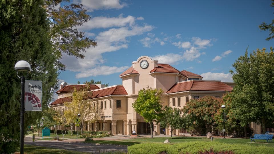 A Pueblo Community College campus building with a clock tower and red tile roofs
